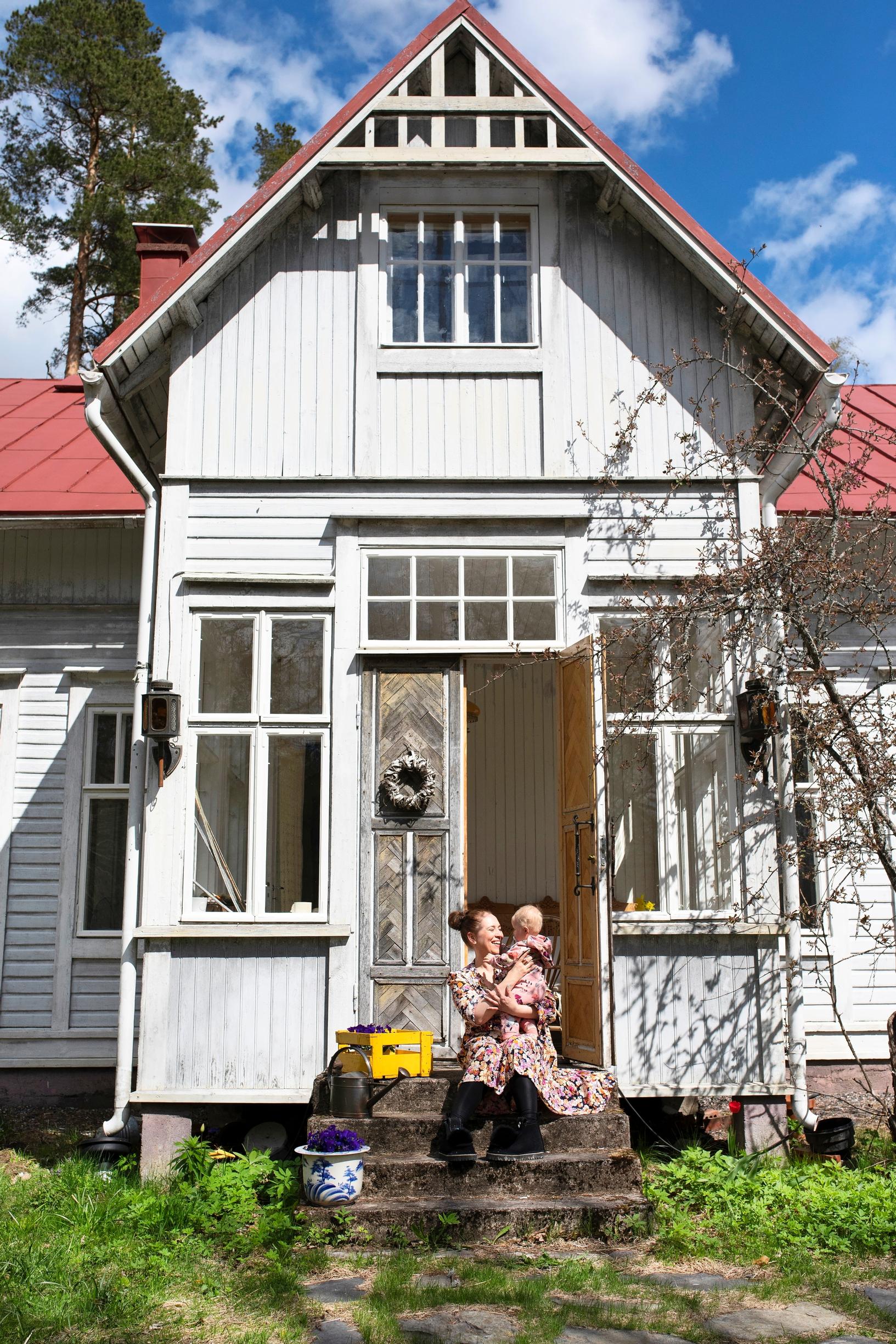 Nainen ja lapsi istuvat vanhan puutalon portailla