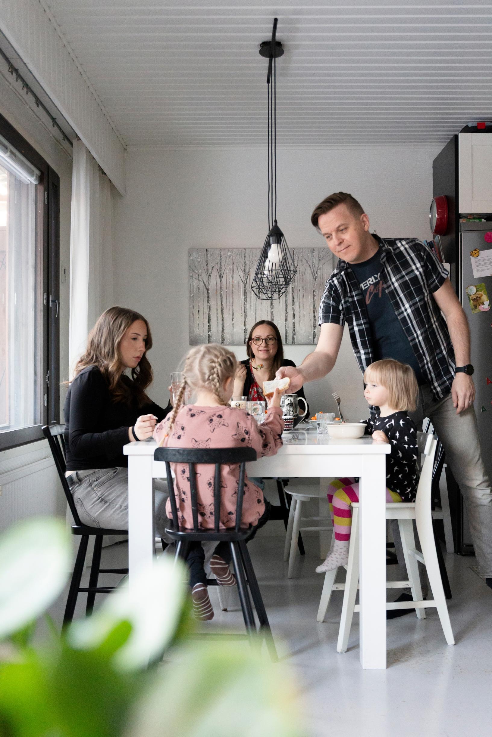 perhe istuu ruokapöydän ääressä