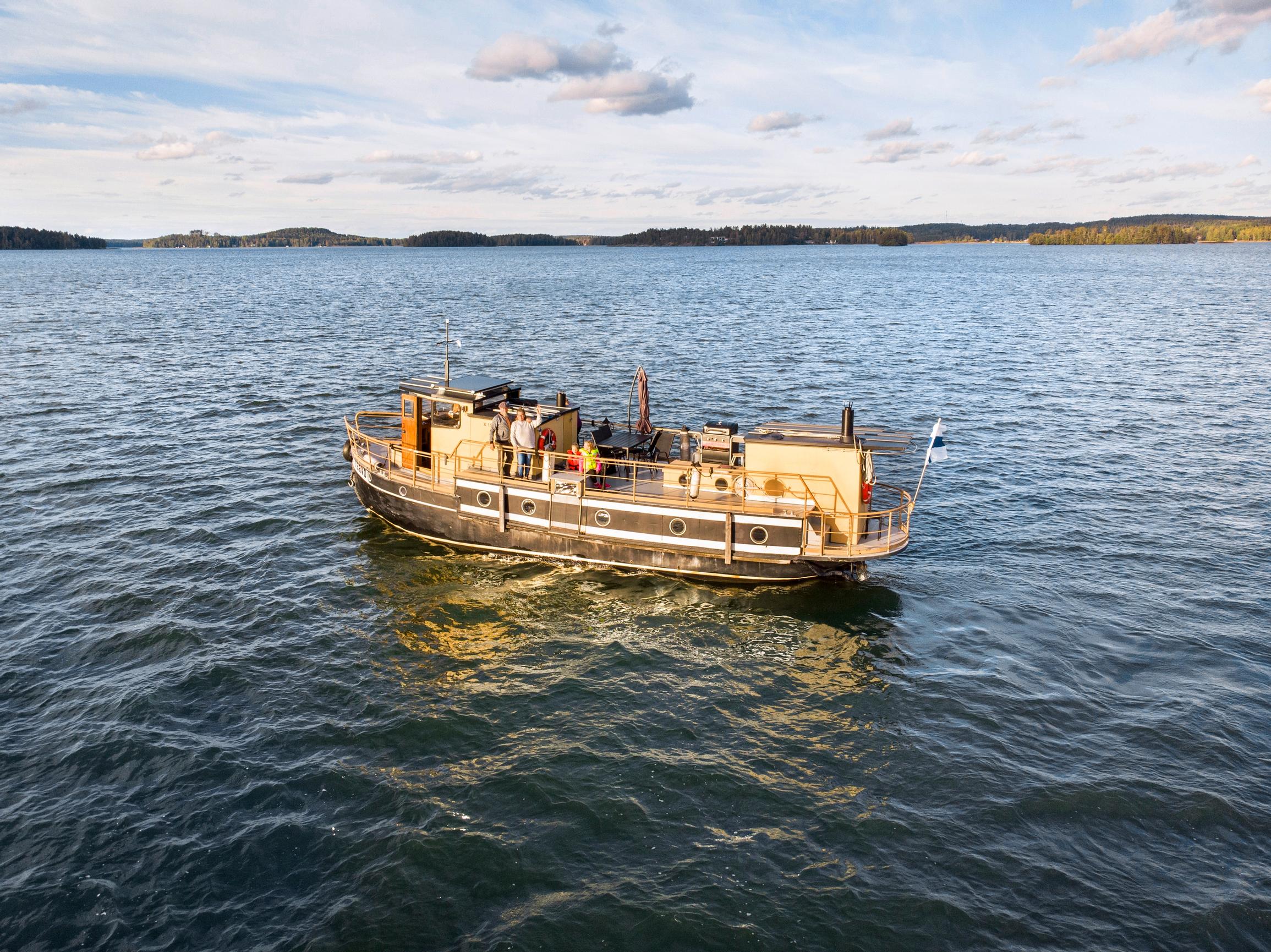 vanha rautalaiva m/s Tervo keskellä järveä, kaksi aikuista ja kaksi lasta kannella
