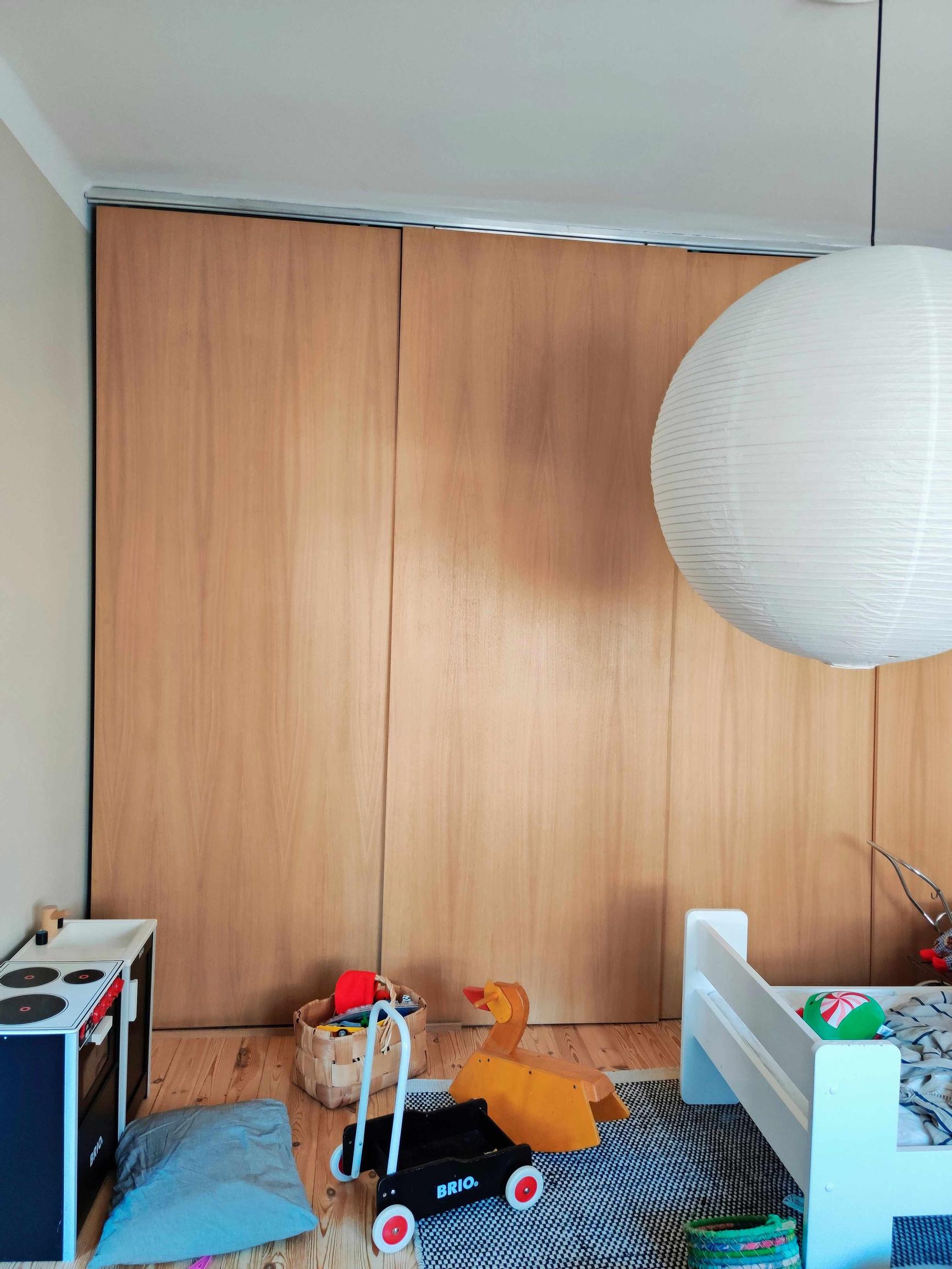 lastenhuone, jossa korkeat puuoviset kaapit, sänky ja leluja