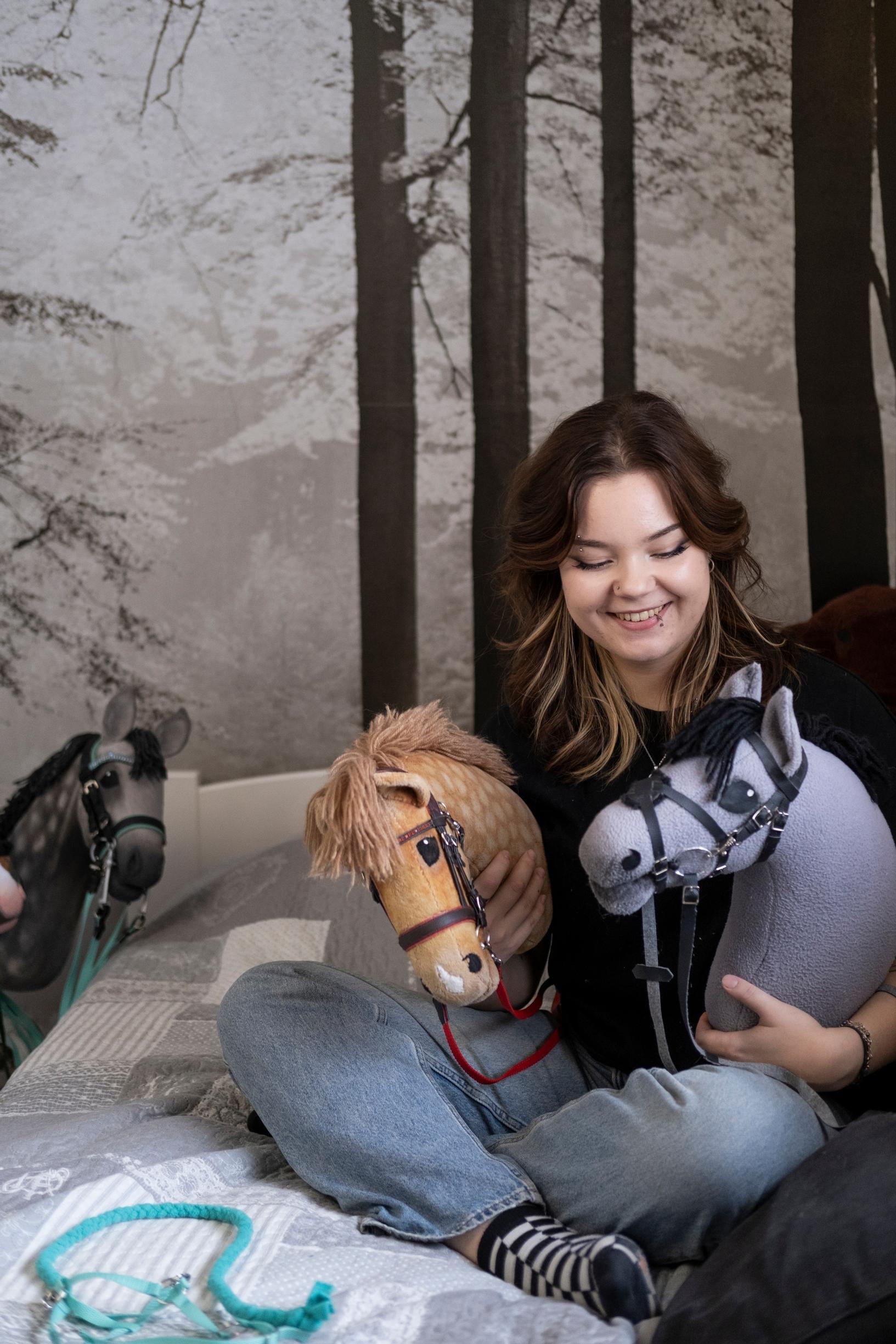 Elinalla on kainalossa kaksi keppihevosta.