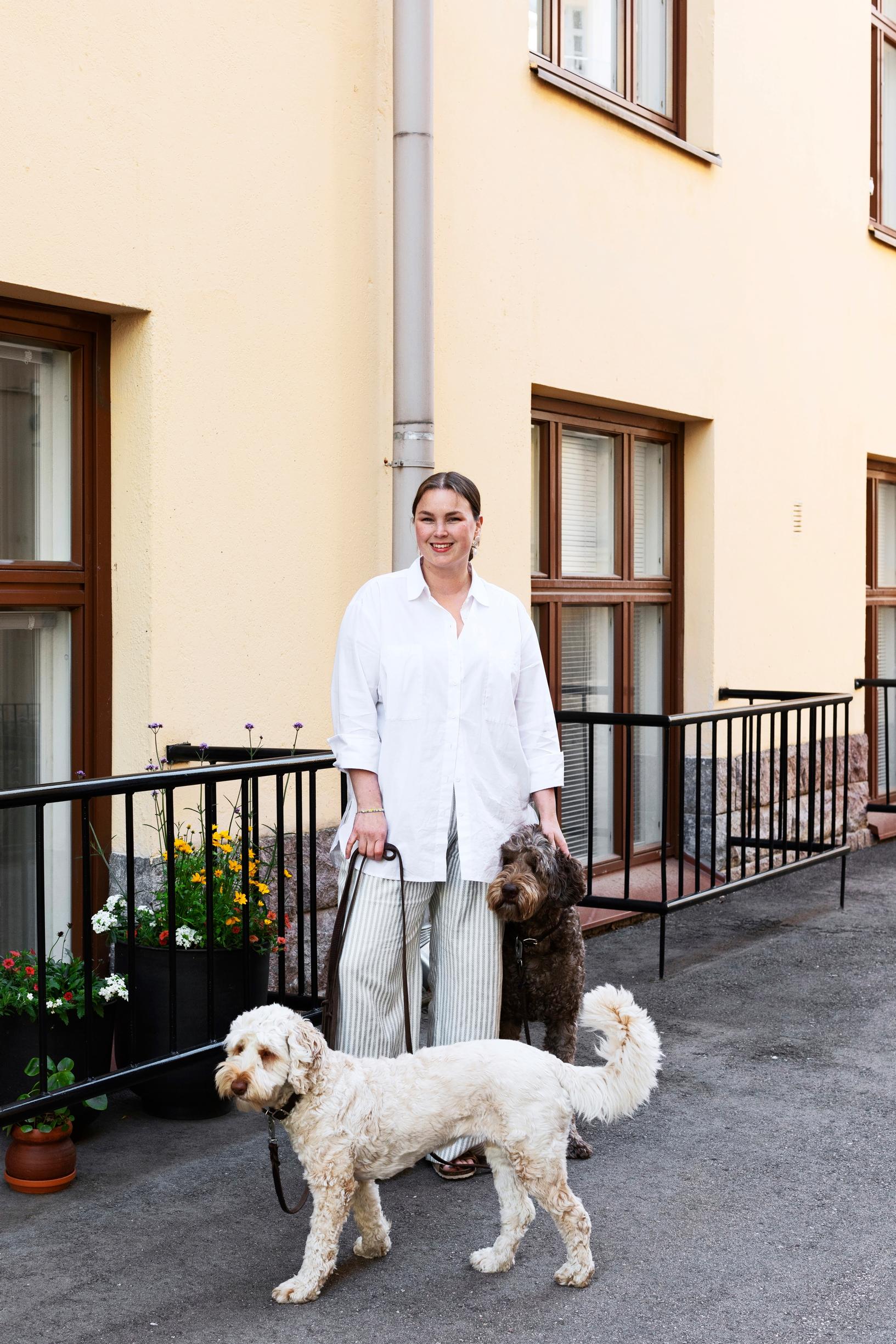 Stylisti Annika Huurrekorpi ja australianlabradoodlet olohuoneen ikkunan edessä