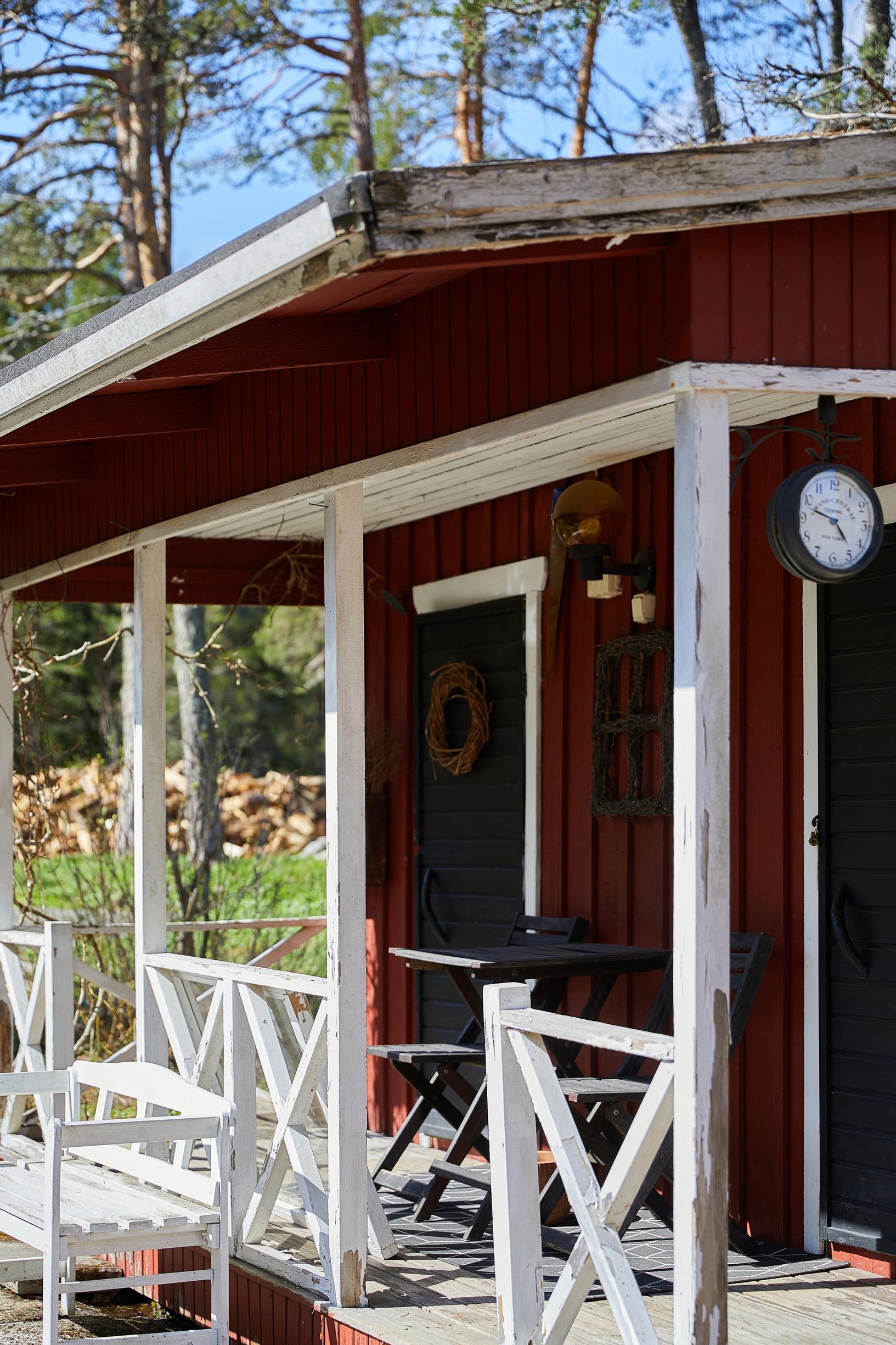 punaseinäinen varasto, valkoiset kaiteet ja valkoinen penkki, musta pöytäryhmä