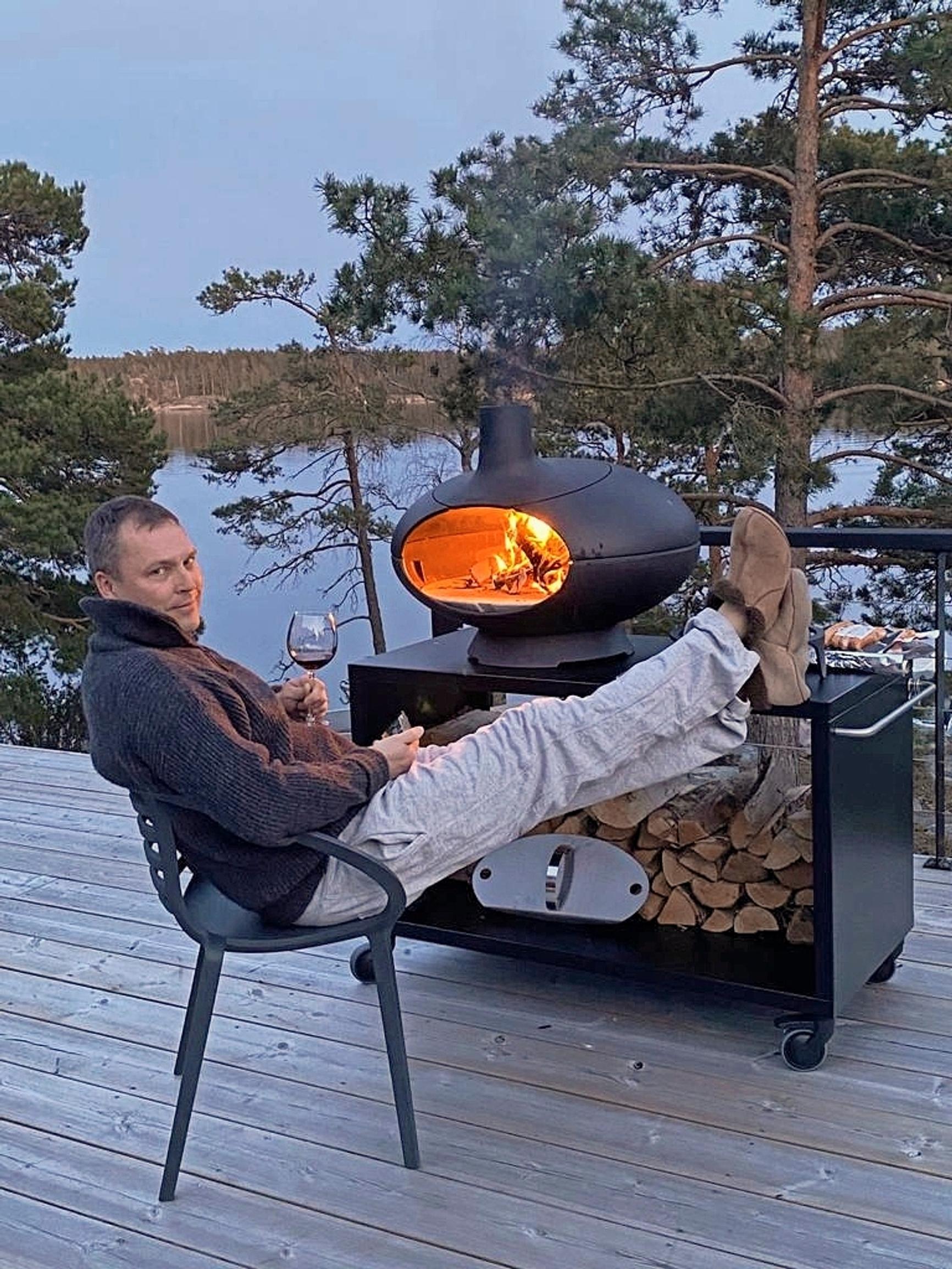 Jani Vahvanen istuu lasi kädessä terassilla pizzauunin luona