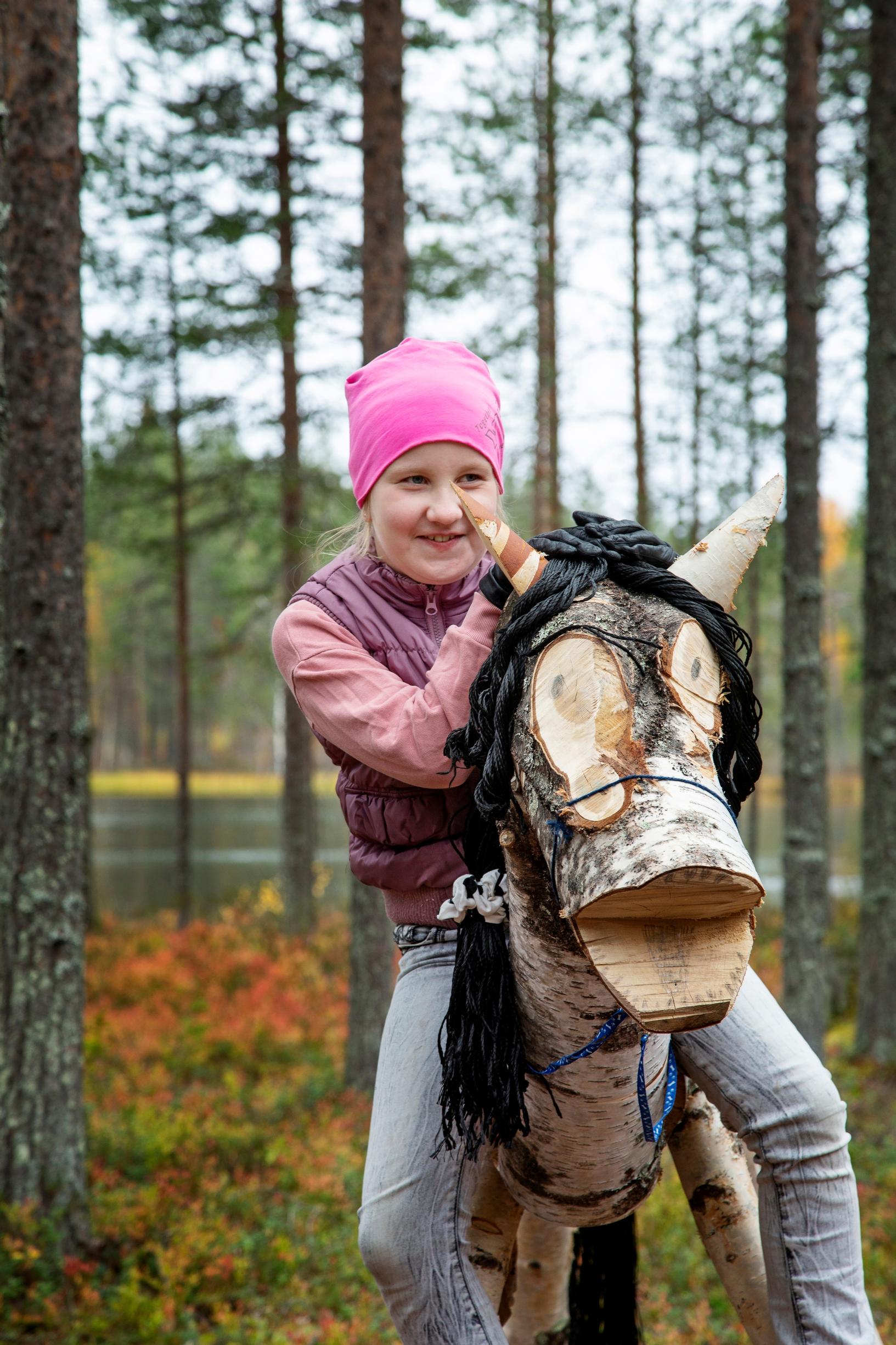 Tyttö puuhevosen selässä