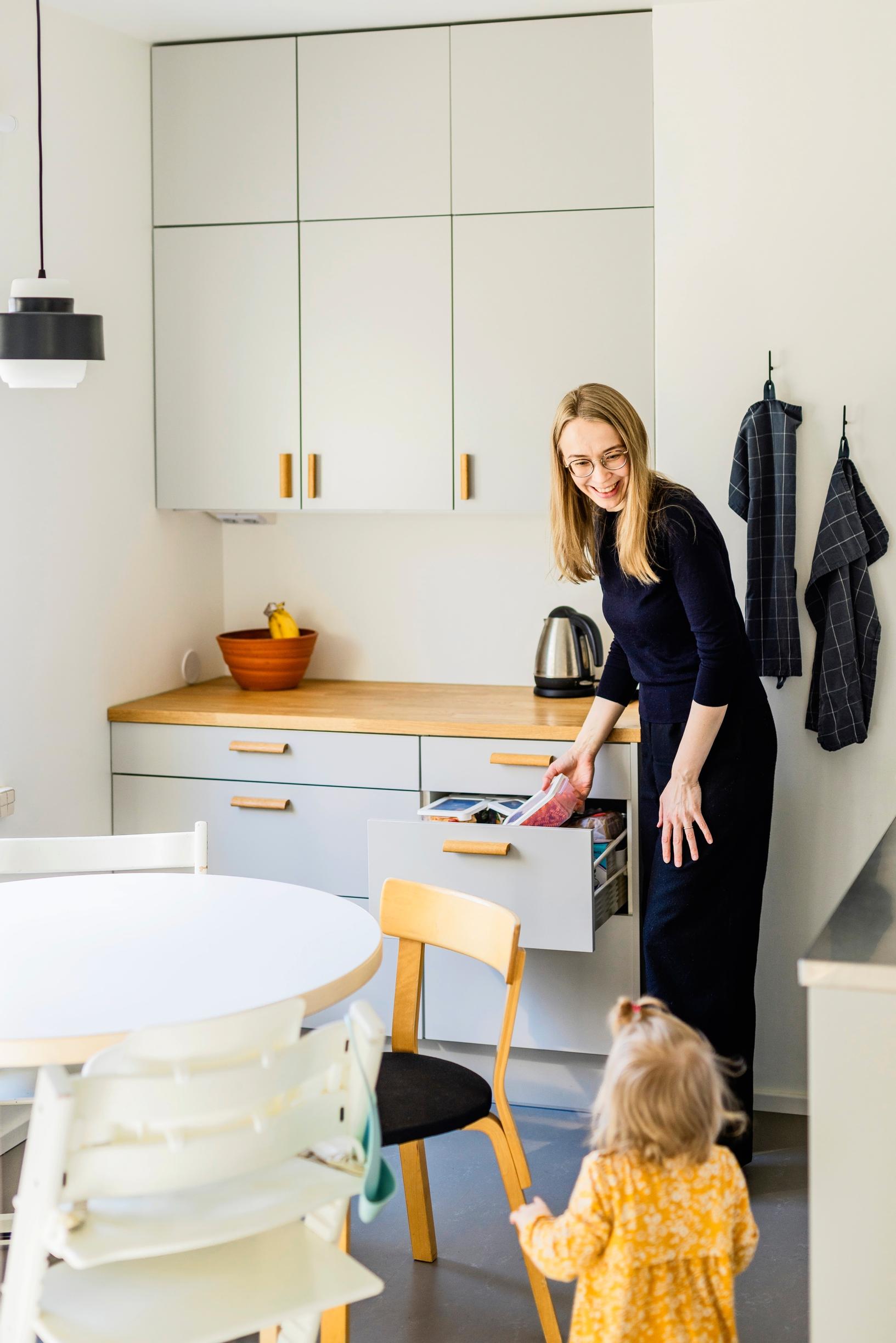 Lapsi seisoo ruokapöydän vieressä keittiössä äidin kanssa