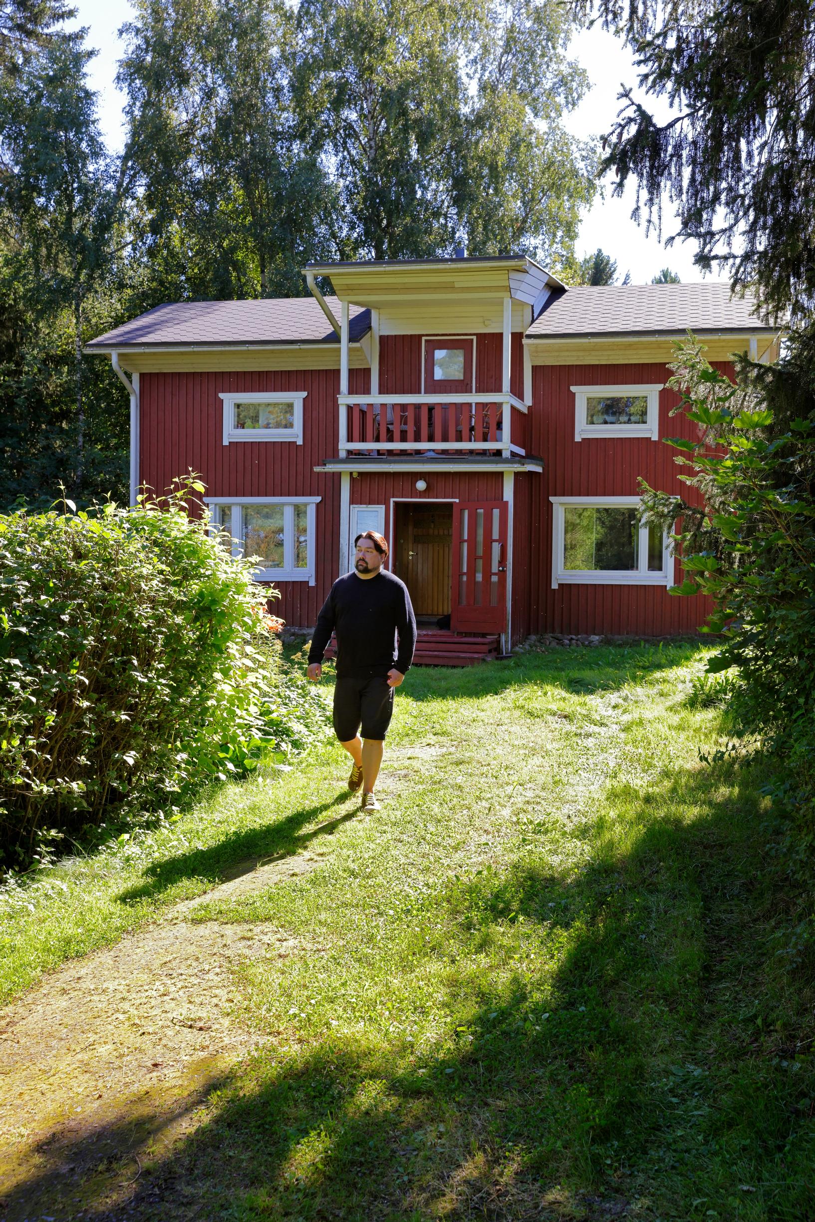 Veikko Halmetoja kävelee punaisen talon pihamaalla
