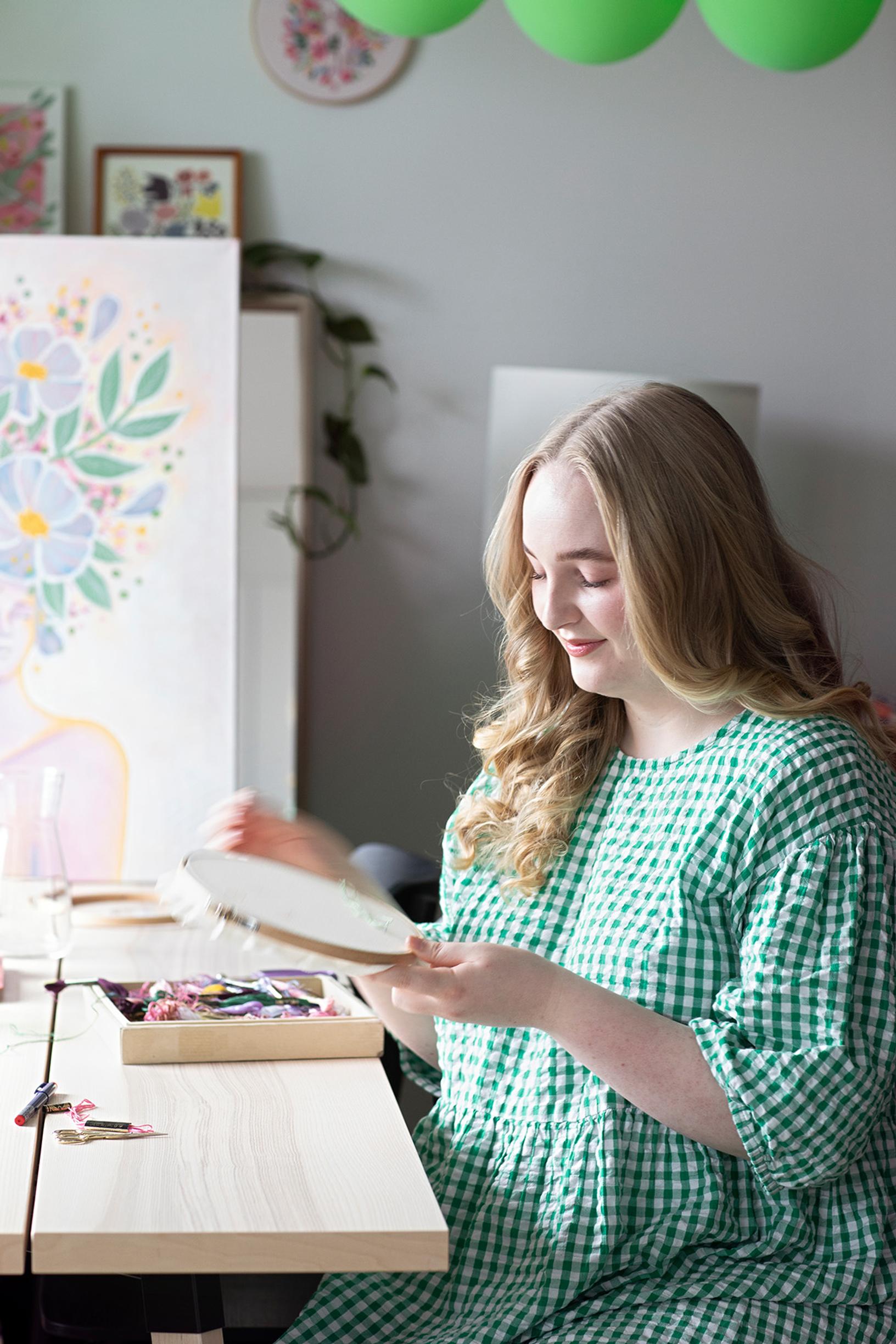 Anna kirjomassa pöydän ääressä
