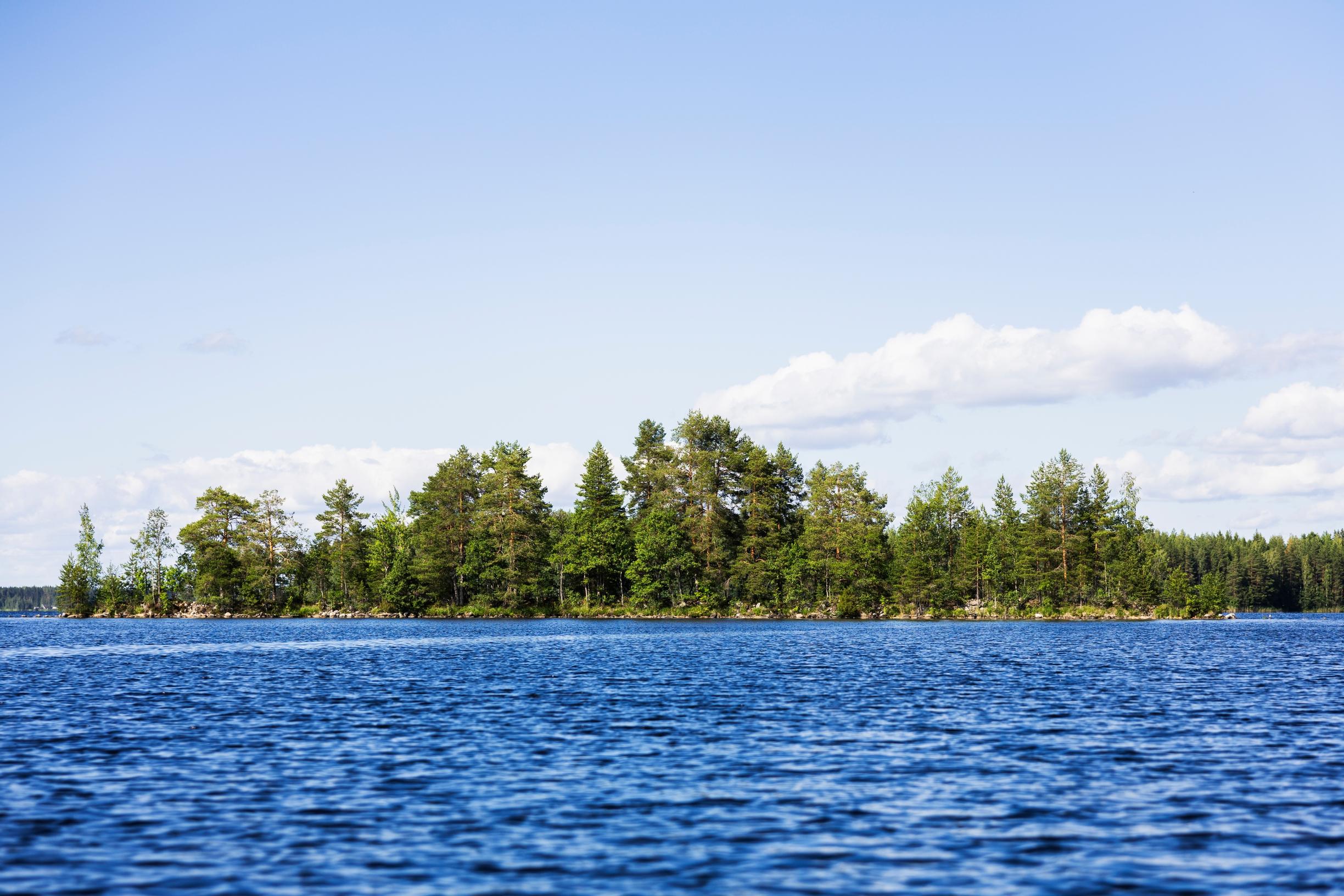 voimakkaan sininen järvi, jonka taustalla puita saaressa