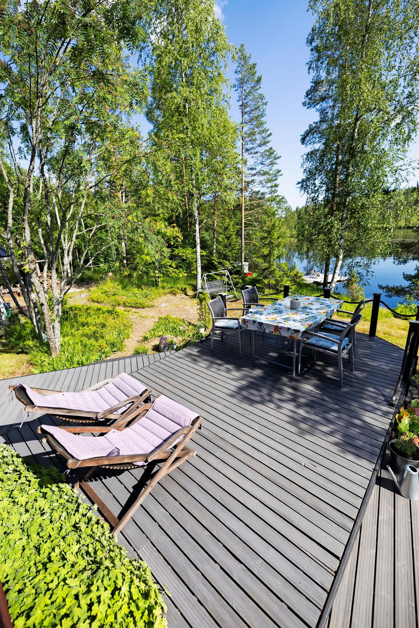 aurinkotuolit ja pöytäryhmä terassilla, taustalla järvi