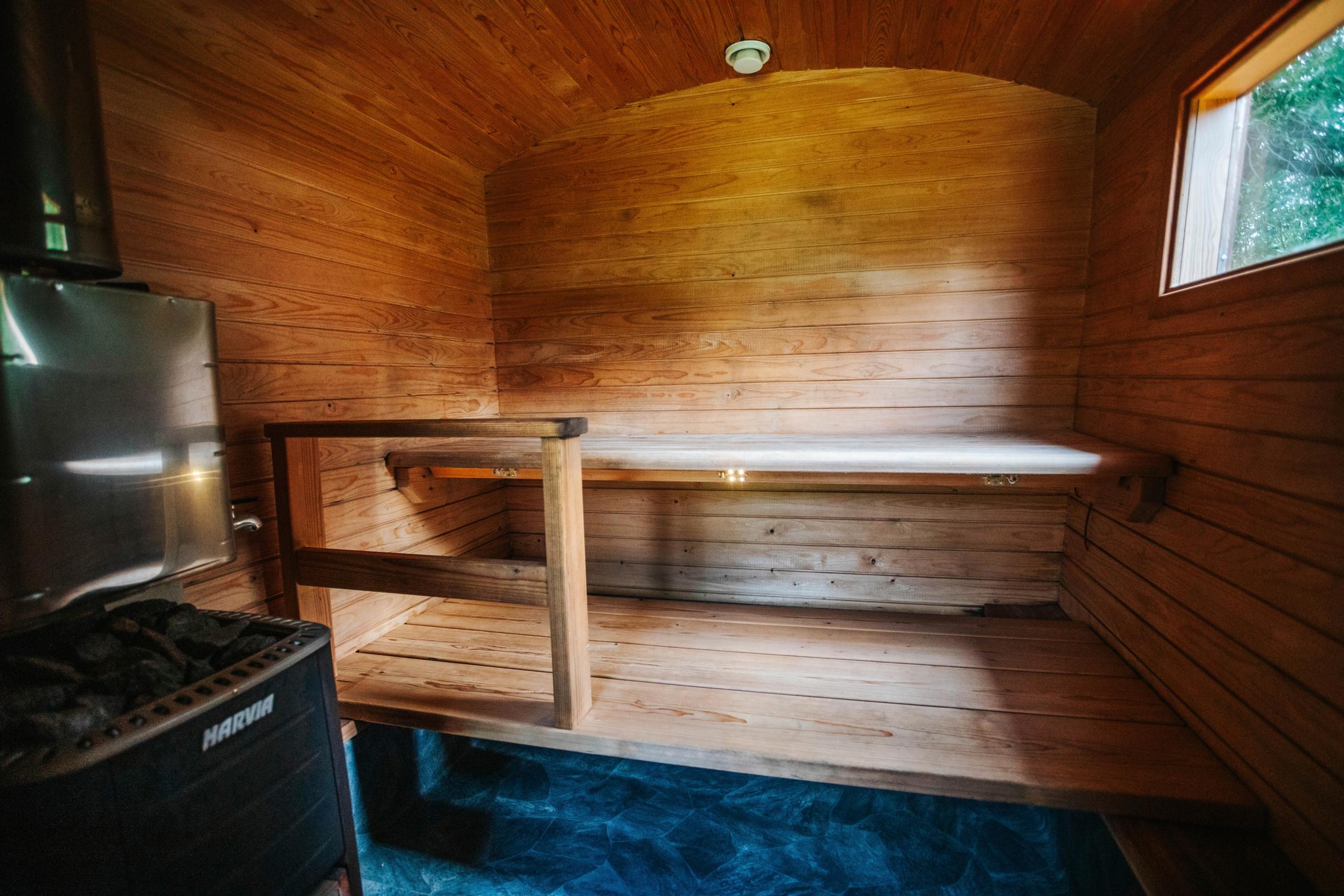 vankkurisauna sisältä, kiuas, lauteet ja ikkuna sekä sininen lattia