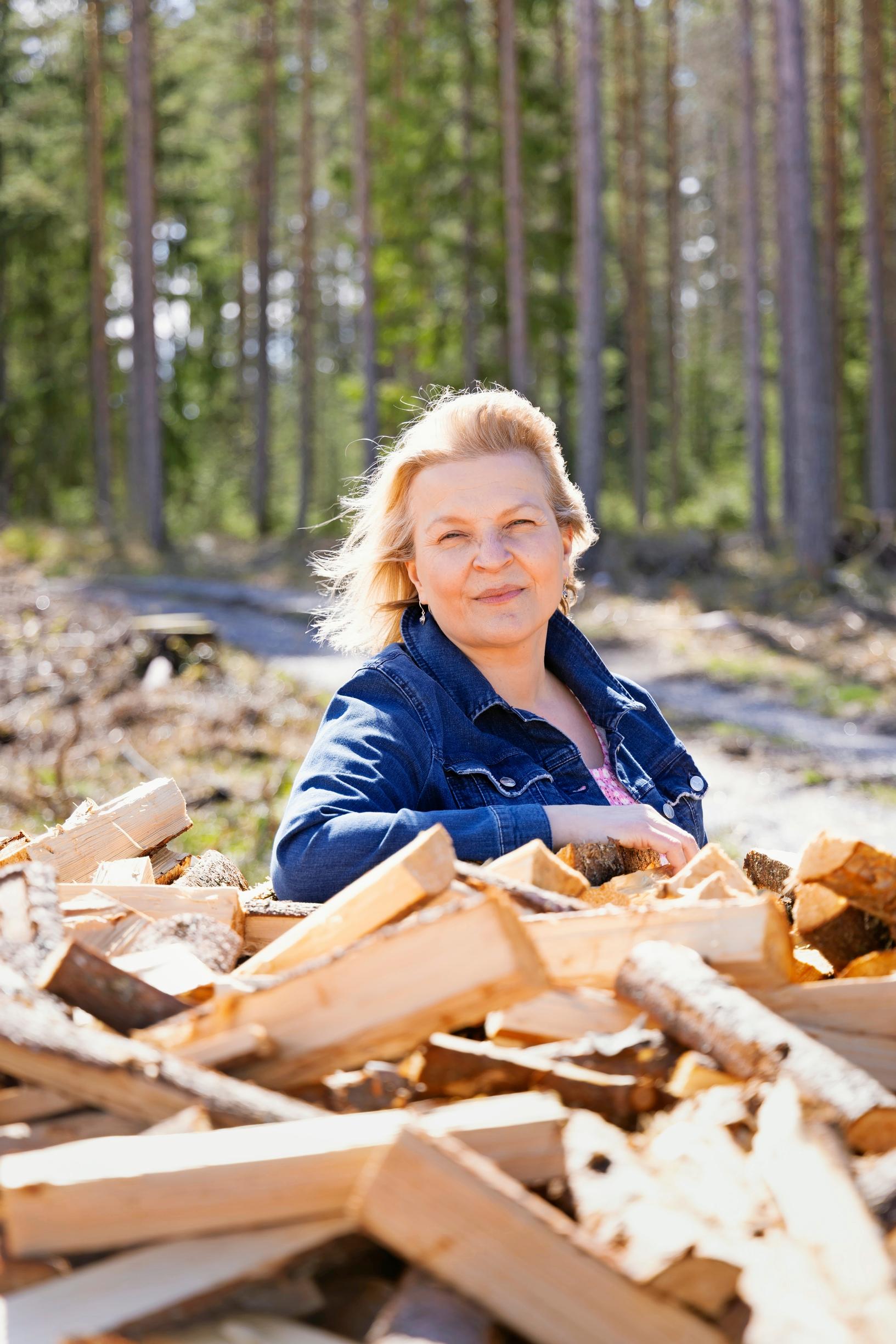 Kirjailija Anu Joenpolvi ja halkopino kodin pihalla
