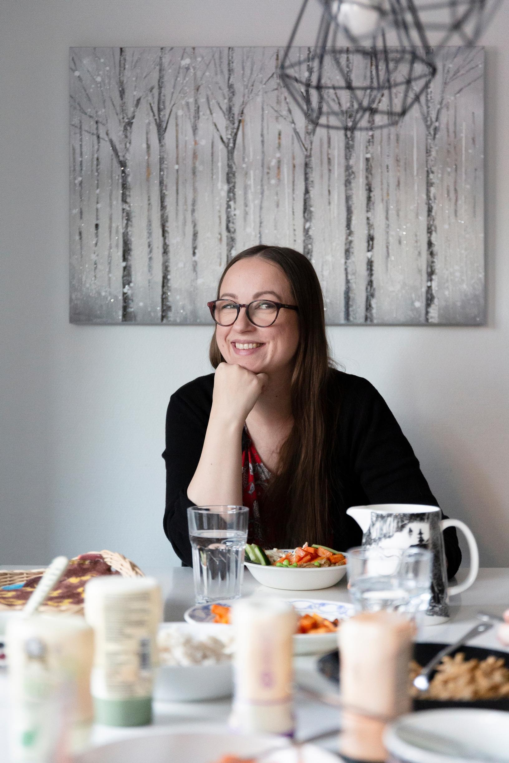nainen istuu ruokapöydän päässä