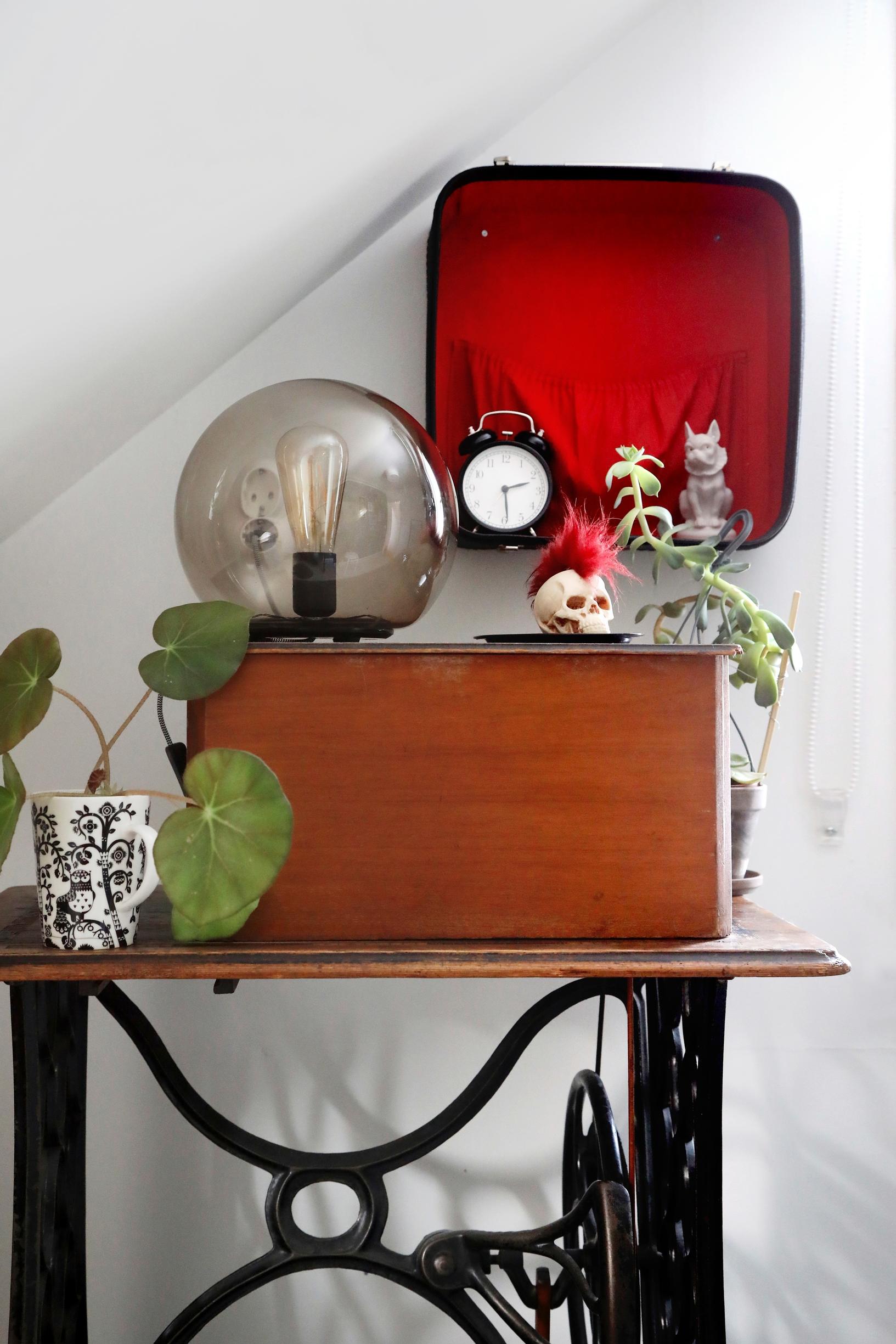 Persoonallisia sisustusesineitä vanhan ompelukonepöydän päällä