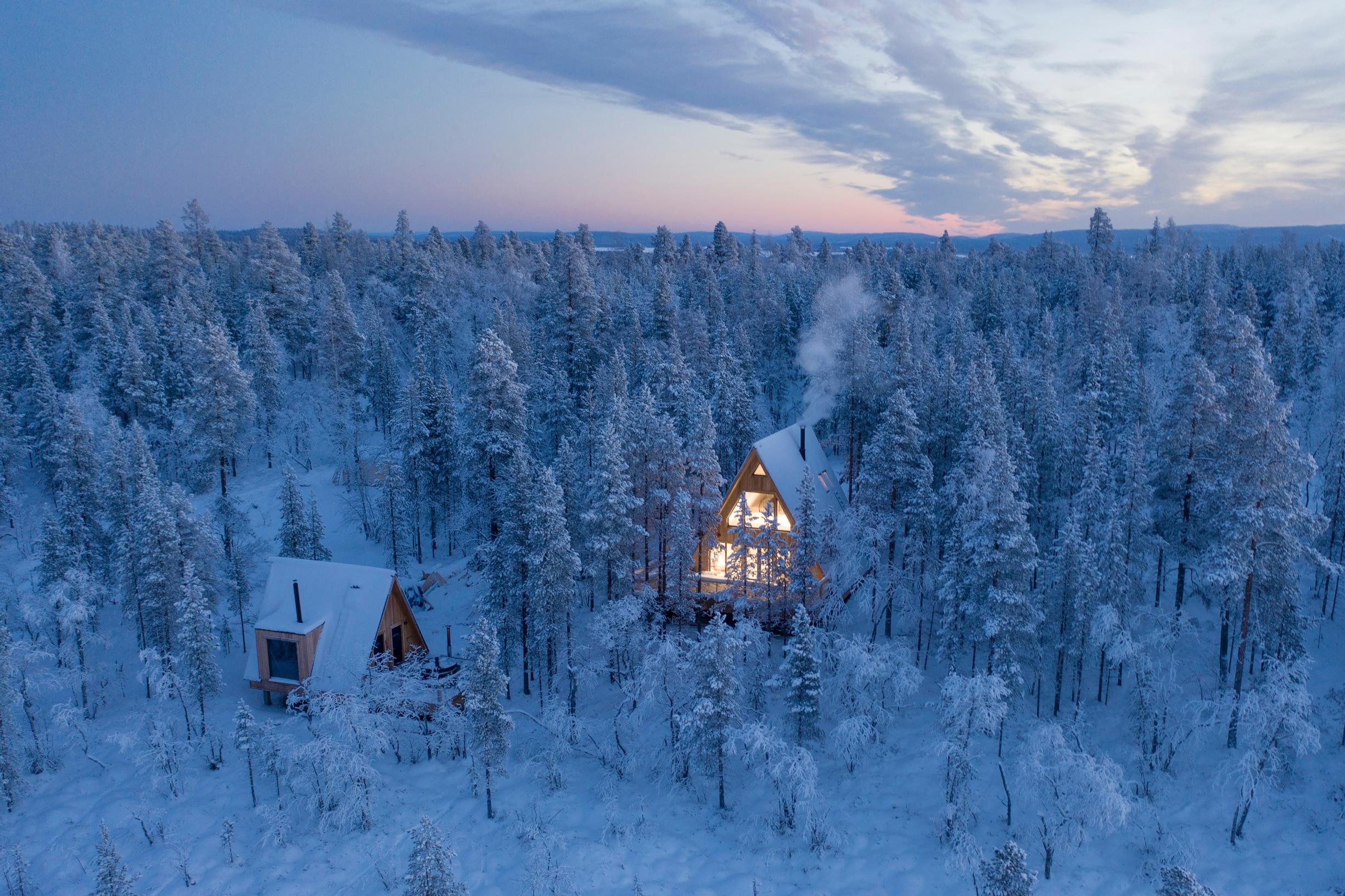 Acarien mökki iltahämyssä keskellä lumista erämaata