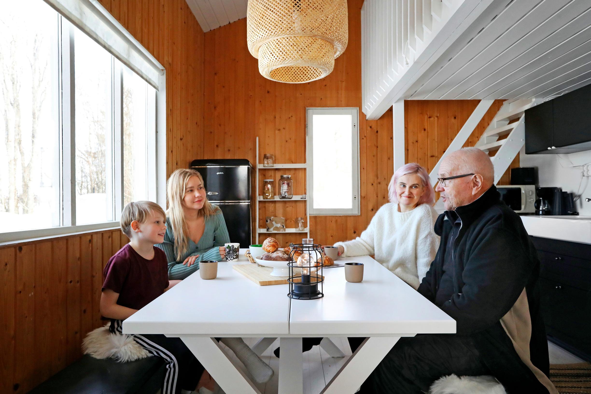 Perhe kahvittelee mökin keittiössä