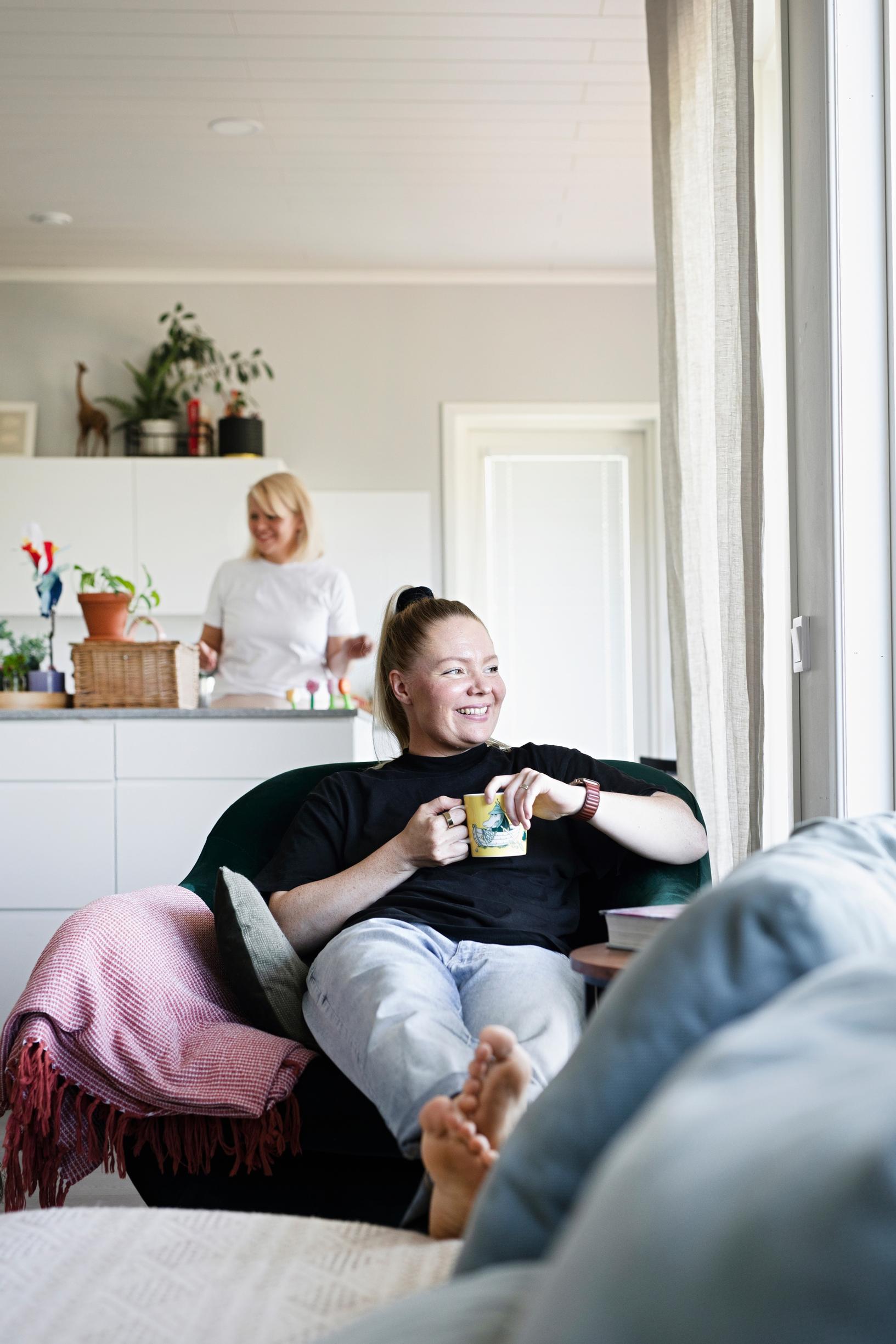 nainen istuu nojatuolissa kuppi kädessään