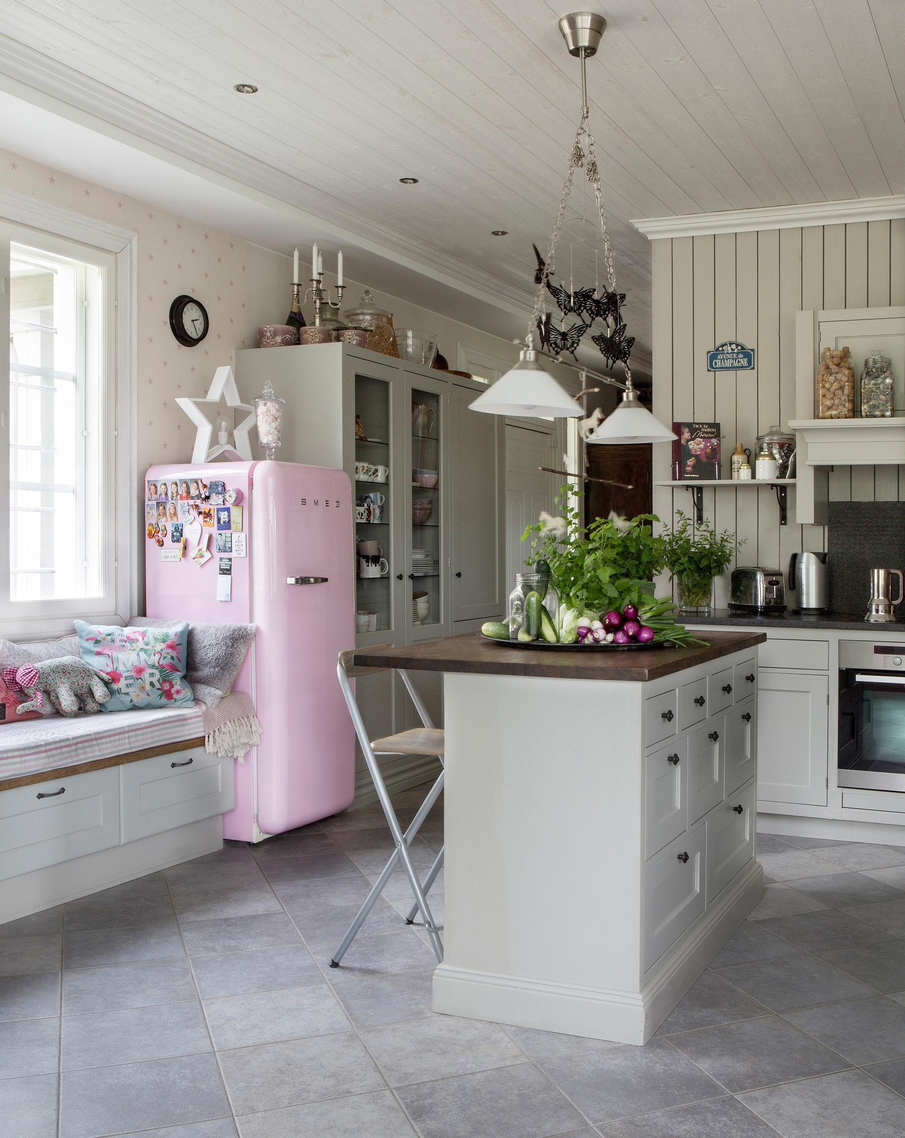 Kokopuinen keittiökaapisto ja saareke sekä pinkki jääkaappi