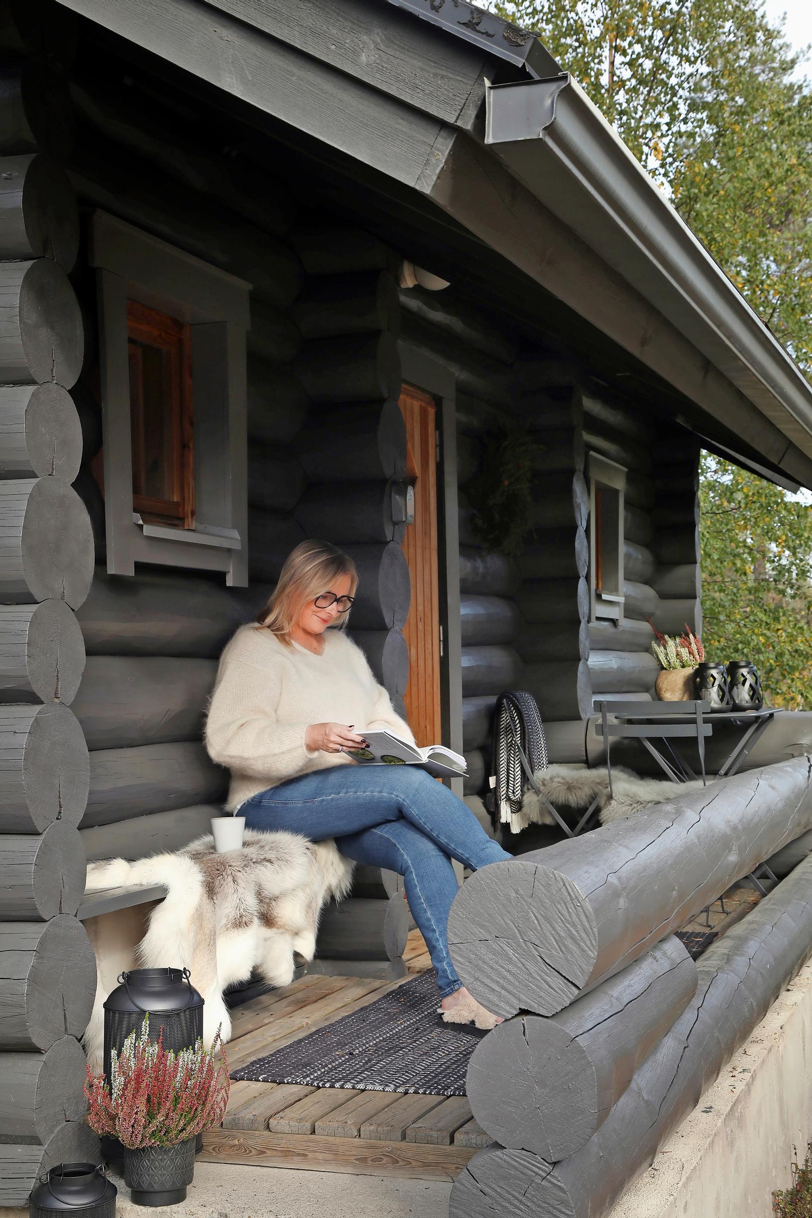 Teija Sääksmäki istuu hirsimökin terassilla