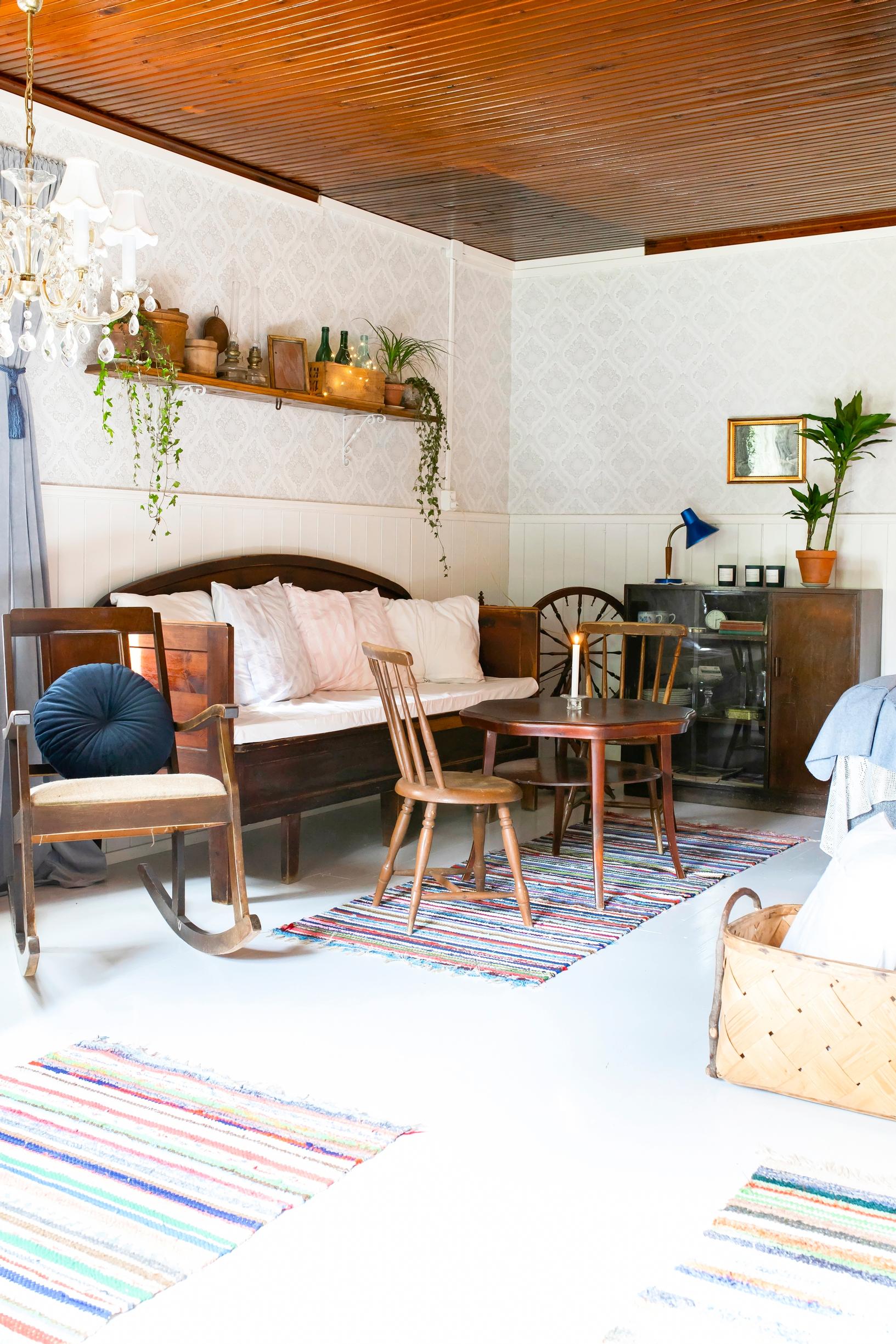 Vanhoja puukalusteita ja räsymattoja mummonmökissä