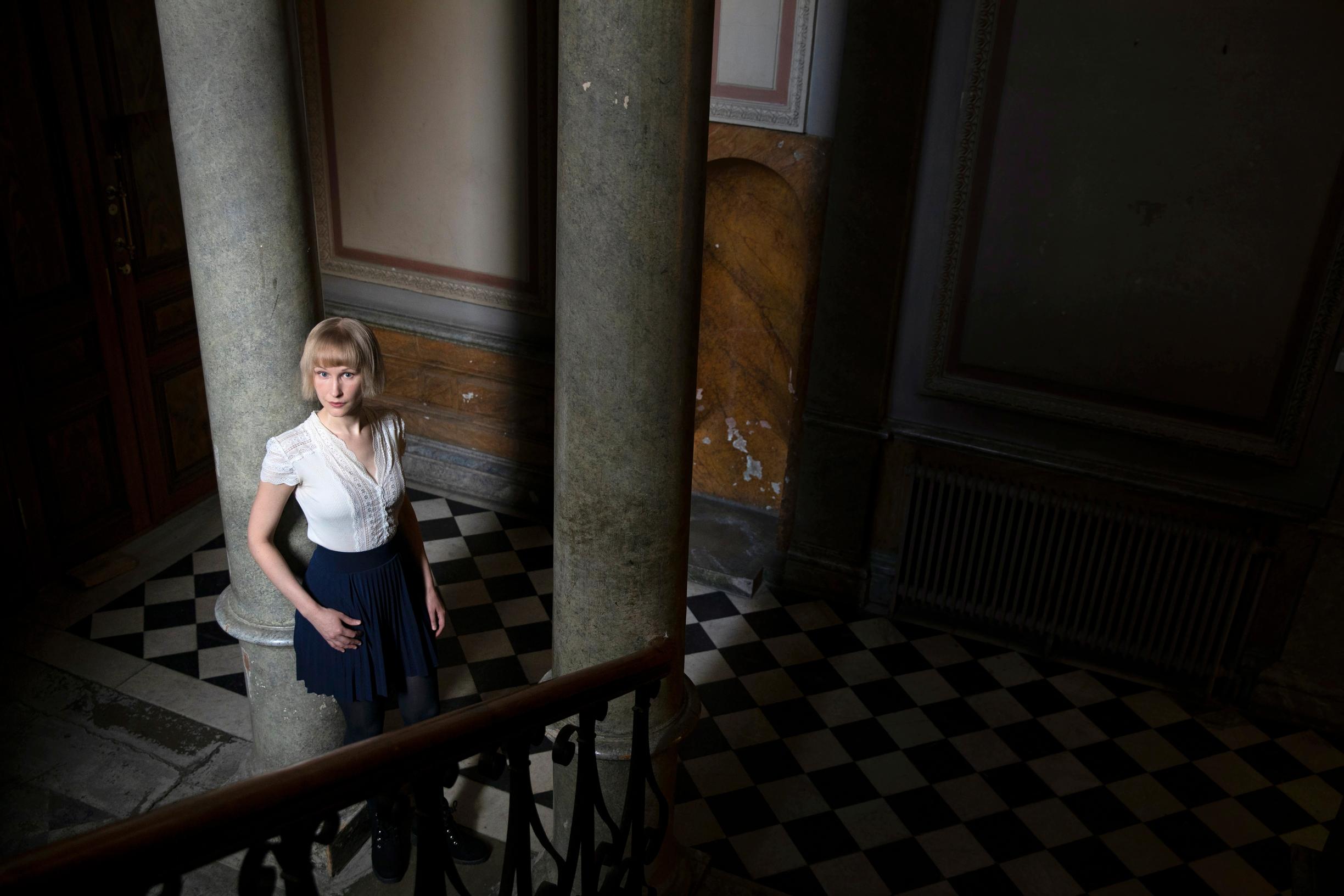 nainen seisoo nojaten pylvääseen