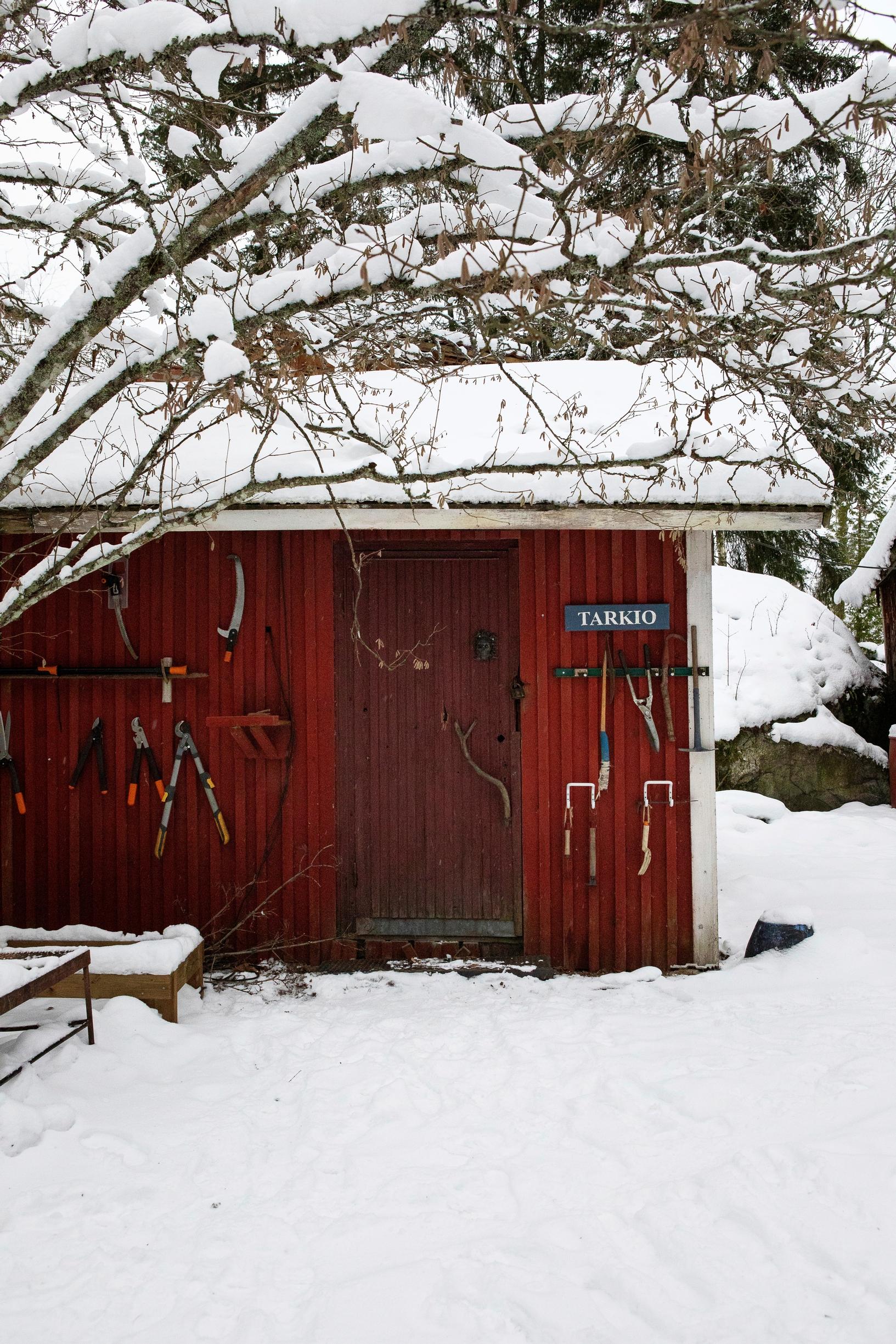 Työkalut on ripustettu pihavajan seinälle.