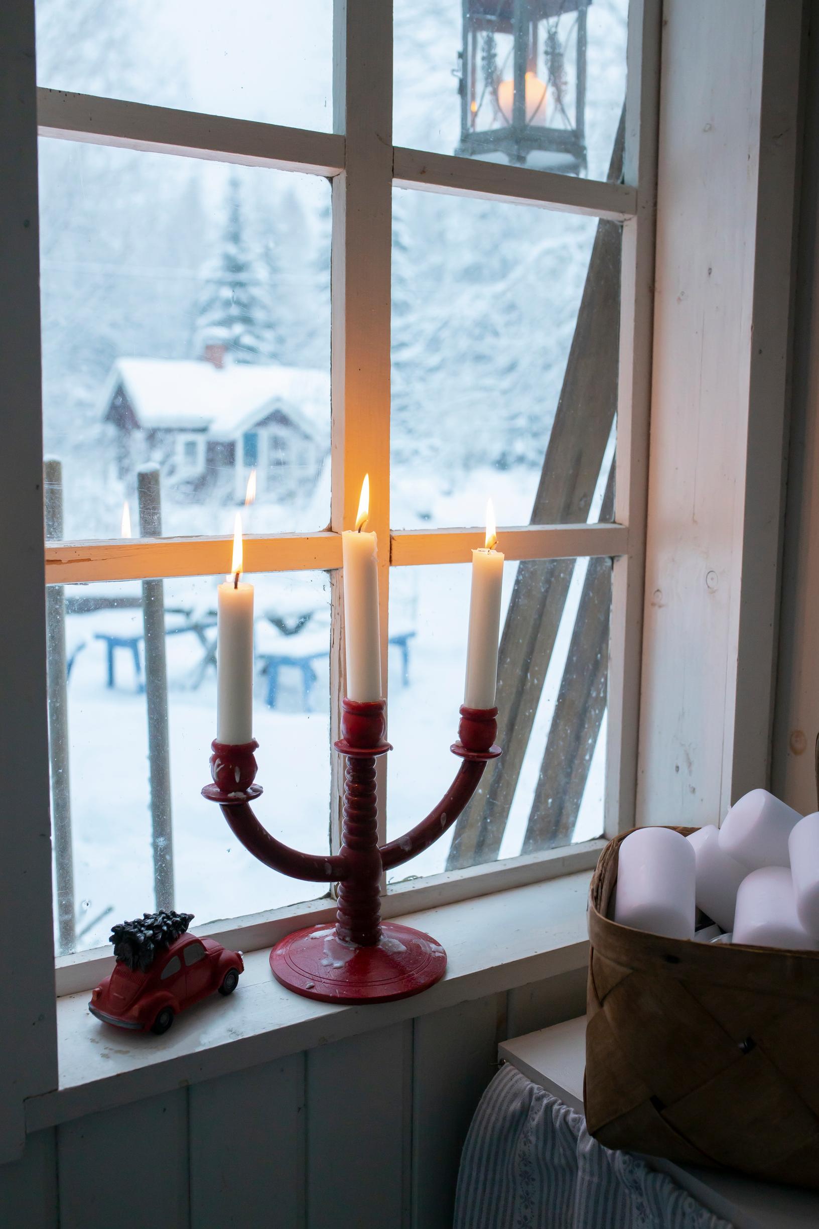 Kynttelikkö ikkunalla, luminen maisema.