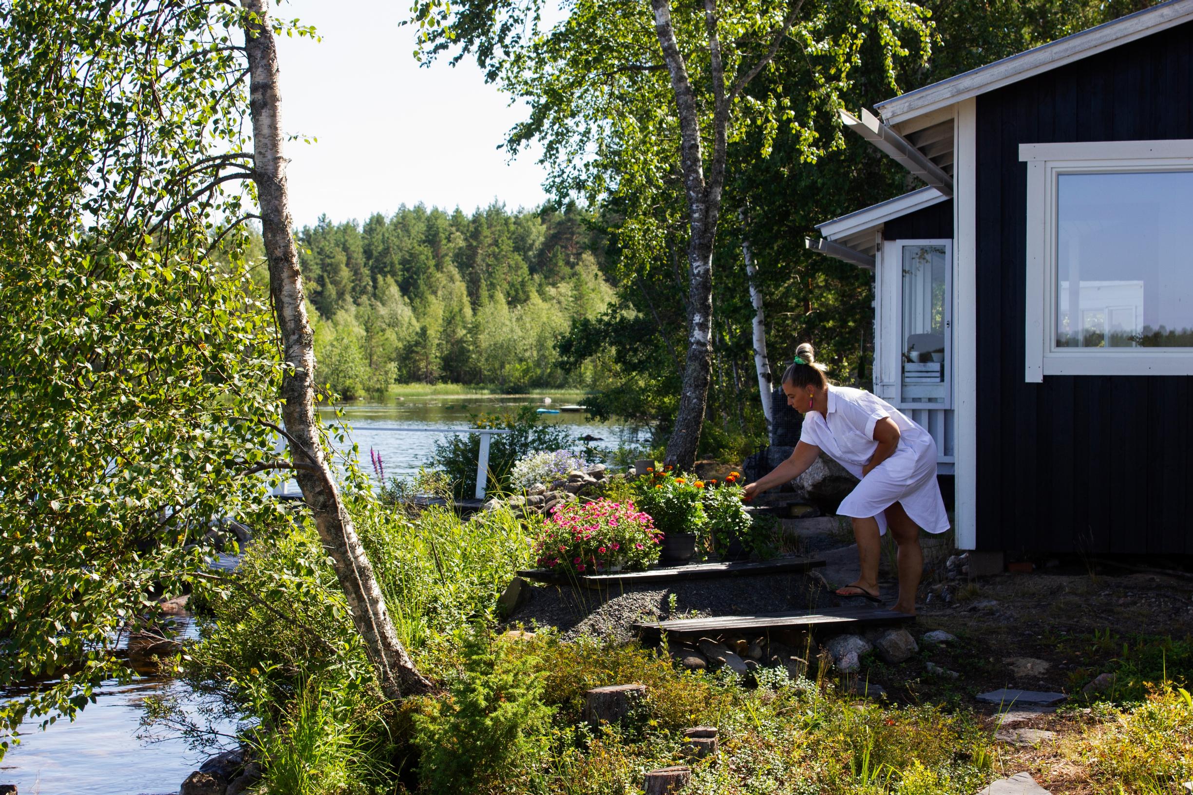 Virva hoitaa ruukkukukkia mökin pihassa